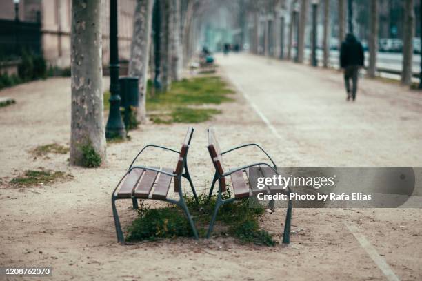 two benches in the boulevard, man walking in the background - early termination foto e immagini stock