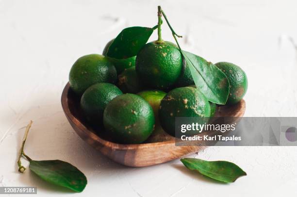 calamondin or philippine lime on a wooden heart-shaped bowl - calamansi stock-fotos und bilder
