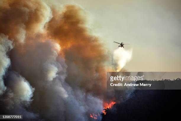 forest fire with firefighting helicopter aircraft water bombing bushfire on mountain at dusk, australia - emergency services australia imagens e fotografias de stock