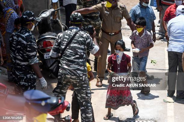 Migrant workers children collect food packets distributed by the Central Reserve Police Force at an industrial area during a government-imposed...