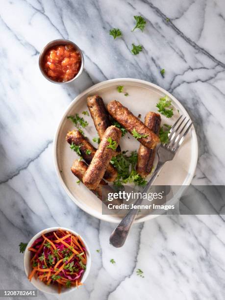 vegan sausages on a white plate with coleslaw and salsa. - sausage - fotografias e filmes do acervo