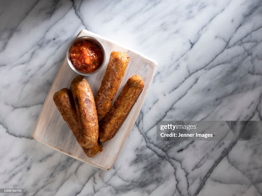 Vegan sausages sitting on a marble bench.