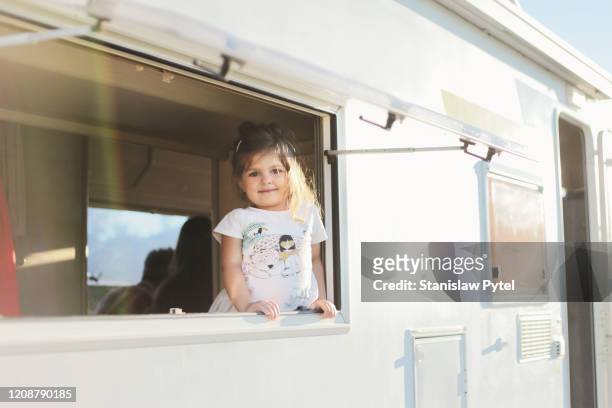 Small girl smiling from campervan's window