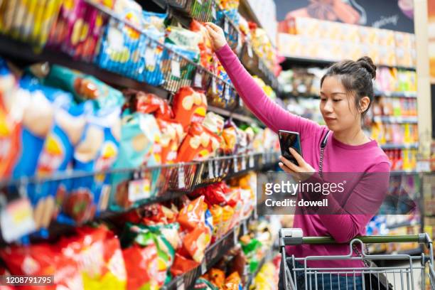 asian female shopping in supermarket - crisps foto e immagini stock