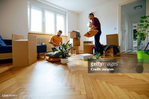 gay couple unpacking together in their new home - gay couple new house stock pictures, royalty-free photos & images