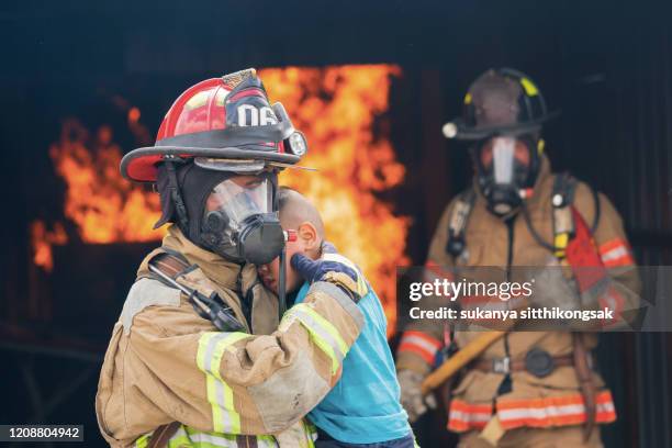 firefighter saving boy in burning house . - brandung bildbanksfoton och bilder