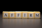 The word AFFIRM written on wooden cubes isolated on a black background