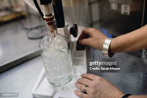 woman fitting stopper in bottle of gin - destillation stock-fotos und bilder