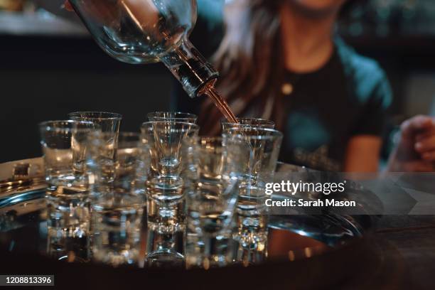 gin being poured into shot glasses on a tray - independent spirit stockfoto's en -beelden