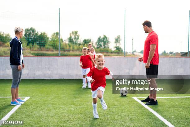a group of children with coach training on football pitch. - calcio di squadra foto e immagini stock