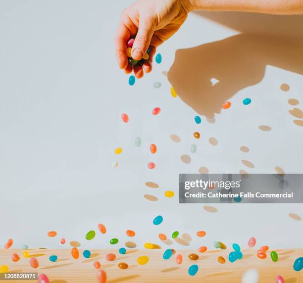 hand sprinkling jelly beans - sprinkles stock-fotos und bilder