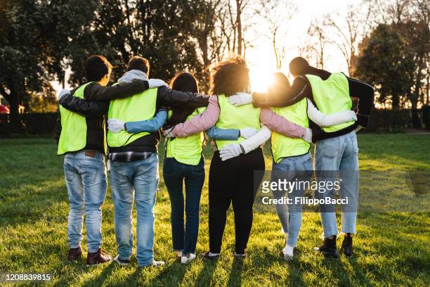 rear view of teenager volunteers embracing together - charity and relief work stock pictures, royalty-free photos & images