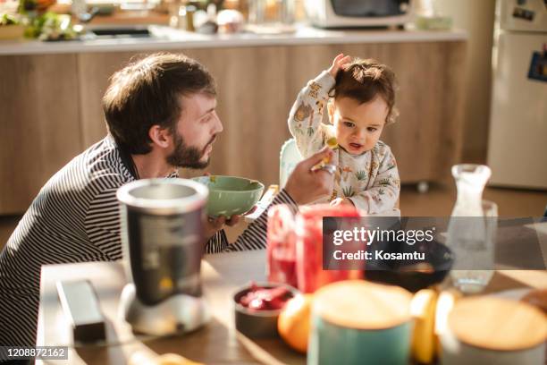 angry baby boy refusing to eat his mashed broccoli baby food - angry parent mealtime stock pictures, royalty-free photos & images