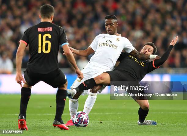 Vinicius Junior of Real Madrid is tackled by Bernardo Silva of Manchester City during the UEFA Champions League round of 16 first leg match between...