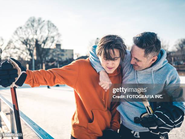 padre e hijo jugando hockey al aire libre - mens ice hockey fotografías e im�ágenes de stock