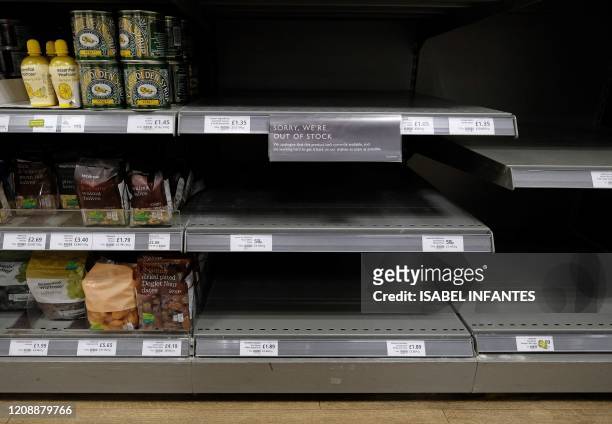 In this file photo taken on March 31, 2020 Empty shelves where packets of flour would normally be stocked are pictured below half-empty egg, and...