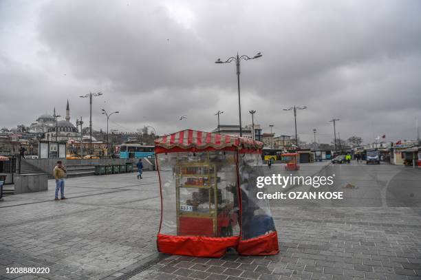 Vendor cover his wheelbarrow with a plastic as he tries to sell Turkish traditional backery "simit" on April 1, 2020 in Istanbul after Turkish...