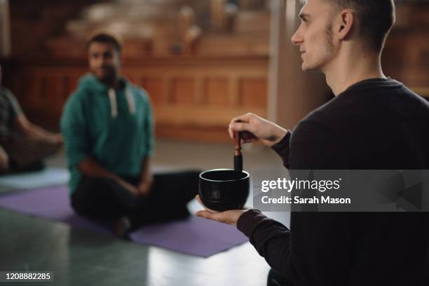 a yoga teacher uses a sound bowl - new age concept photos et images de collection