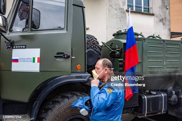 Soldier from the Russian military stands near a decal on a Russian military truck with Russian and Italian flags that reads "From Russia with Love"...