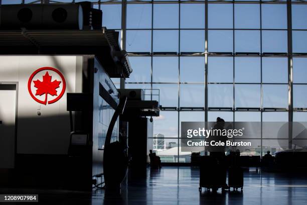 Passenger wheels her luggage near an Air Canada logo at Toronto Pearson International Airport on April 1, 2020 in Toronto, Canada. Air Canada...