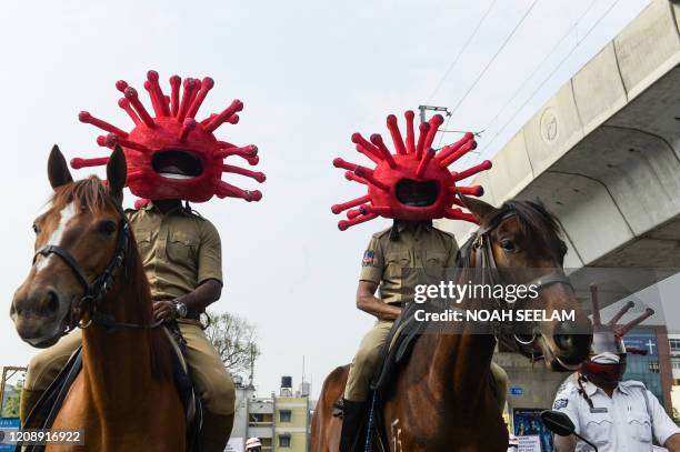 Police personnel wearing coronavirus-themed helmets ride on horses as they participate in a awareness campaign during a 21-day government-imposed...