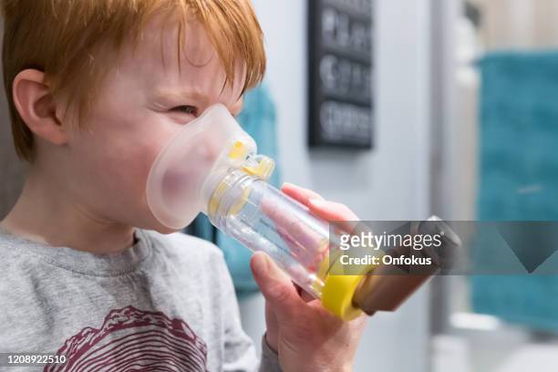 joven niño recibiendo tratamiento respiratorio de la madre - nebulizador fotografías e imágenes de stock