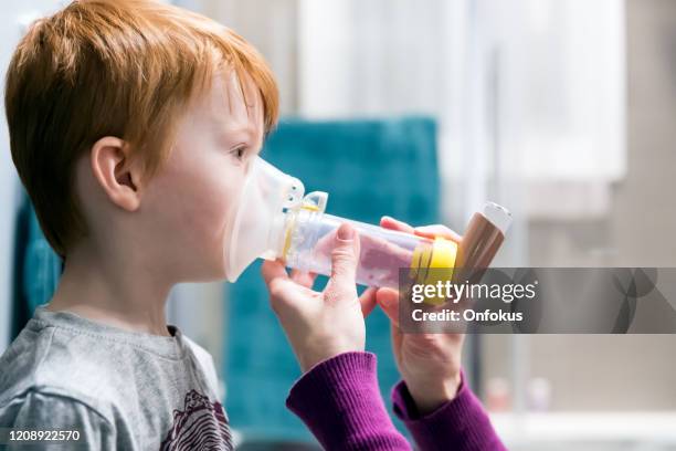 young boy getting breathing treatment from mother - childhood asthma stock pictures, royalty-free photos & images