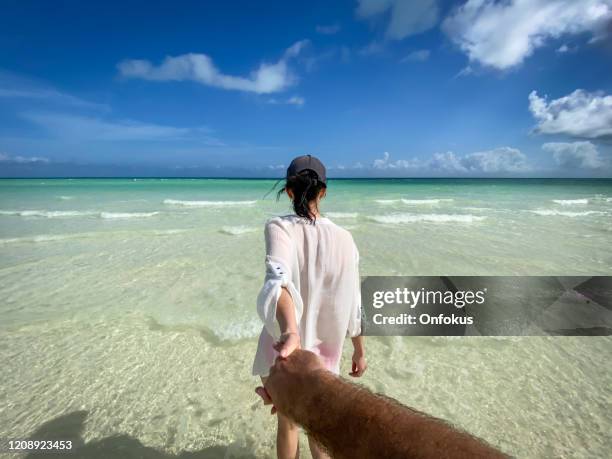 follow me concept - beautiful woman holding her husband's hand on tropical beach in the caribbean - cuba beach stock pictures, royalty-free photos & images
