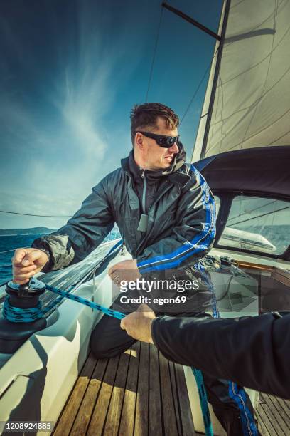 mann auf dem segelboot mit einer seilwinde - kabelwinden stock-fotos und bilder