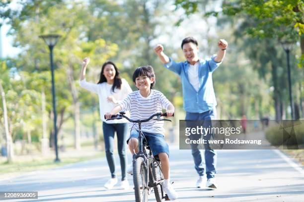 parent practicing their son riding cycling - asian cycling stock pictures, royalty-free photos & images