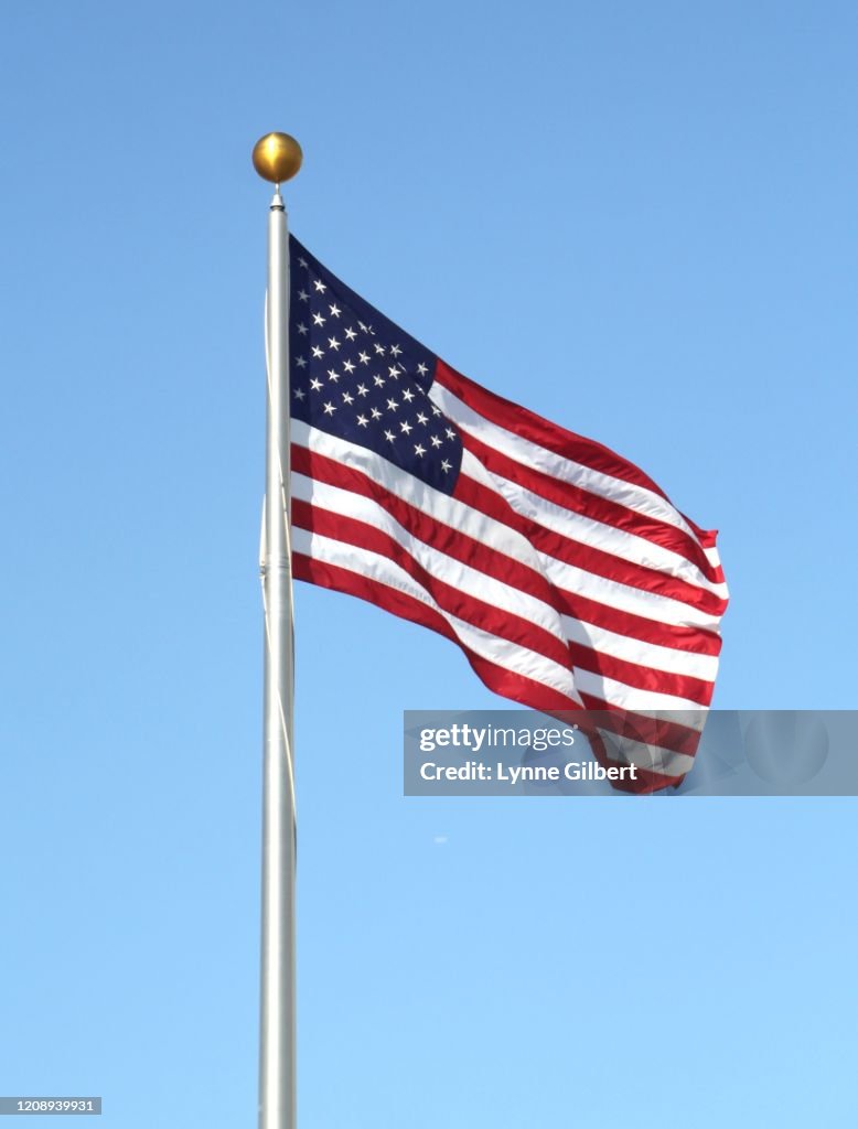 An American flag blows in the wind with a beautiful blue sky