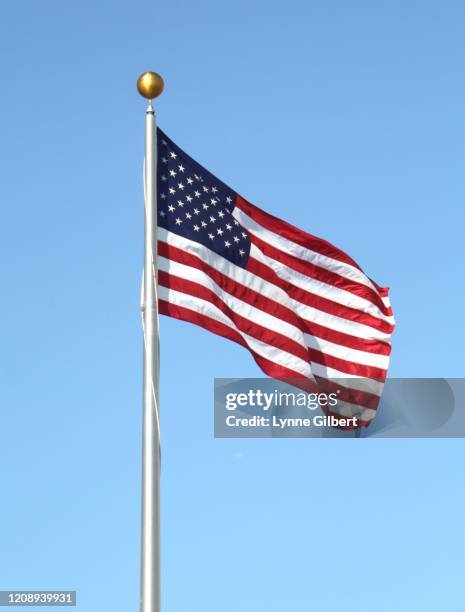 an american flag blows in the wind with a beautiful blue sky - american flag jpg stock pictures, royalty-free photos & images