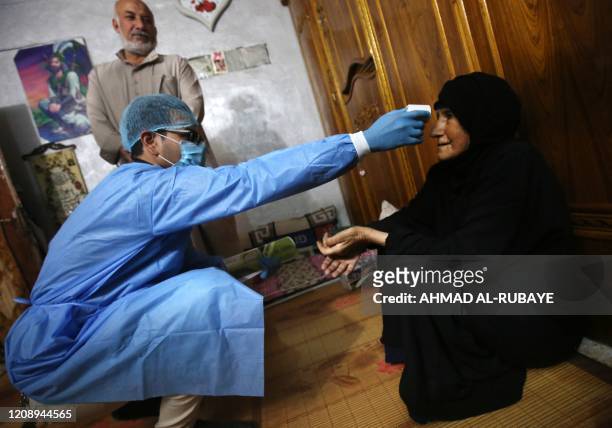 An Iraqi public hospital specialised doctor checks a woman's temperature for COVID-19 in the capital Baghdad's suburb of Sadr City on April 2 as part...