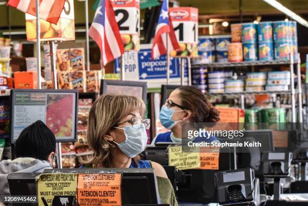 Cashiers wearing protective masks work in a grocery store in the Bushwick neighborhood of Brooklyn on April 2, 2020 in New York City. New York City...
