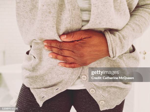 african-american woman experiences stomach pain - kidney stone foto e immagini stock