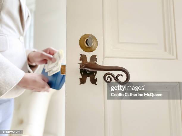 african-american woman holds wallet and pays cash at front door - trinkgeld stock-fotos und bilder