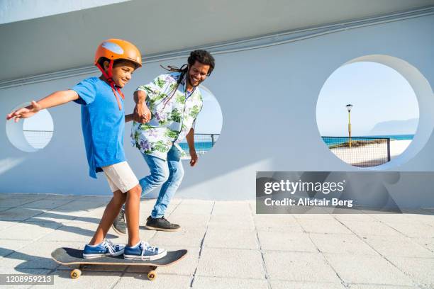 father helping his son to skateboard - father helping son wearing helmet stock pictures, royalty-free photos & images