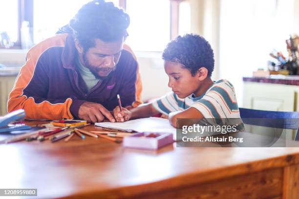 father helping son with his homework at home - self discipline imagens e fotografias de stock
