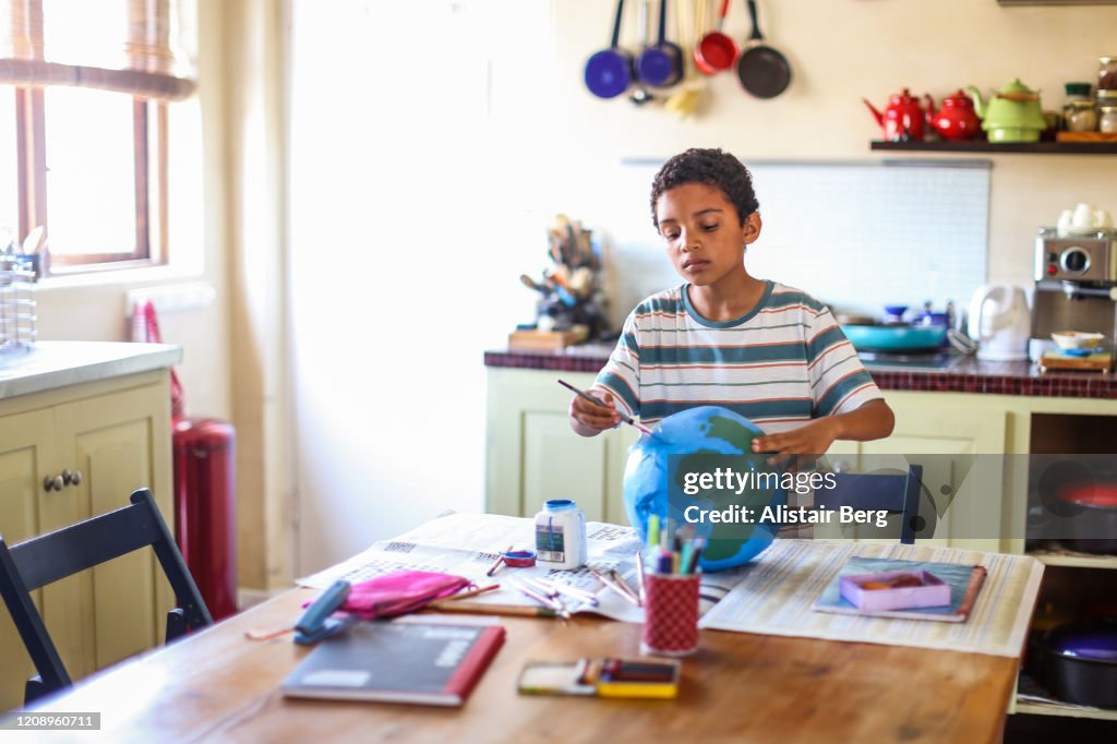 Father helping his son make a globe in his kitchen at home