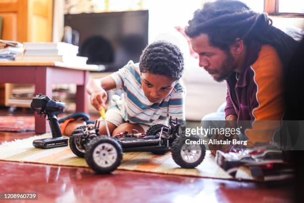 father and son playing with remote control car - vivere semplicemente foto e immagini stock