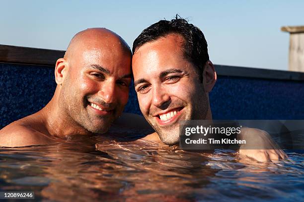 male couple in pool embracing and smiling - indian men gay stock-fotos und bilder