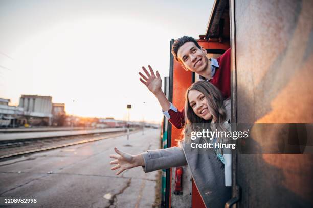 young couple waving from the train - wave hello outside stock pictures, royalty-free photos & images