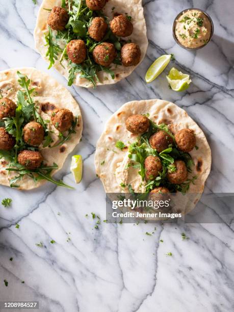 vegan meatballs on flatbreads with hummus dip and rocket leaves. - fleischersatz stock-fotos und bilder