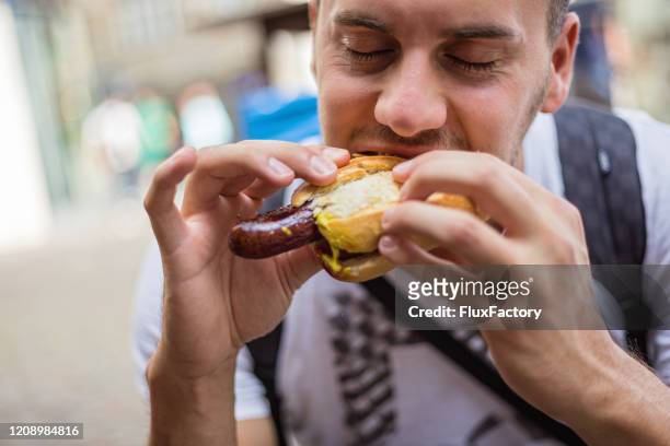 male tourist enjoying delicious famous german sausage - sausage stock pictures, royalty-free photos & images