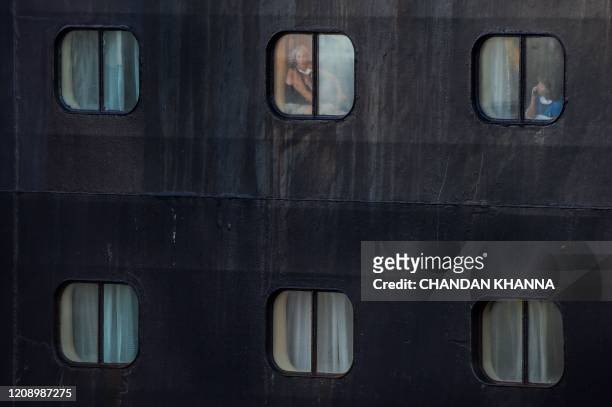 Passengers look out the window of Holland America's cruise ship Rotterdam as it docks at Port Everglades in Fort Lauderdale, Florida on April 2,...