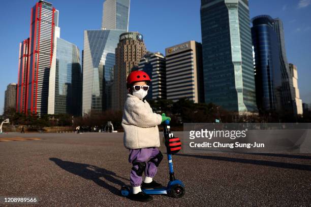 South Korean child wears a mask to prevent catching the coronavirus while riding a scooter on February 27, 2020 in Seoul, South Korea. The government...
