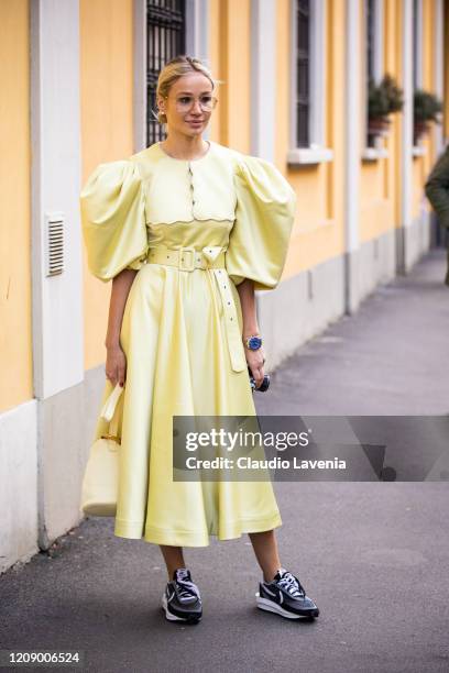 Guest, wearing a yellow maxi dress, yellow bag and Nike sneakers, is seen outside Tod's show, during Milan Fashion Week Fall/Winter 2020-2021 on...