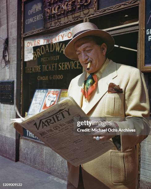 Broadway Sam, a local personality, reading Variety magazine in front of the Broadway Piccadilly theatre ticket service in New York City, circa 1945.