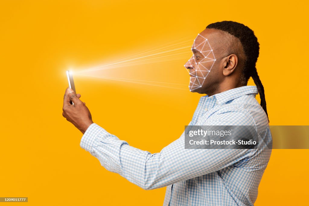 Mature african man scanning his face with mobile app