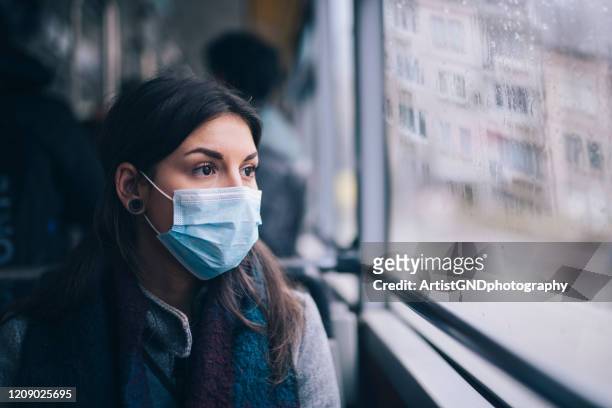 worried woman with protective face mask in bus transport. - protective face mask stock pictures, royalty-free photos & images